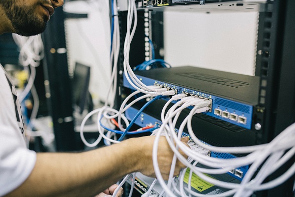 Ein Mann installiert einen Server, in dem er LAN-Kabel steckt.